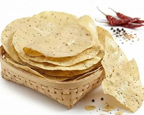 Udad papad with black pepper in a bamboo basket, with dried red chillies